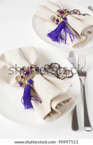 two white china plates, linen napkins on the plates with vintage napkin rings, table decorated with braided hearts.