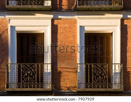 Typical windows and balconies in the Spanish city of Madrid under the warm setting sun.
