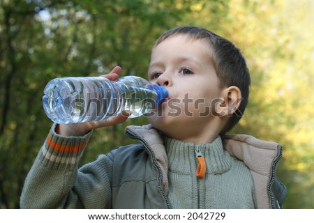 five years old boy drinking mineral water - resting in the forest