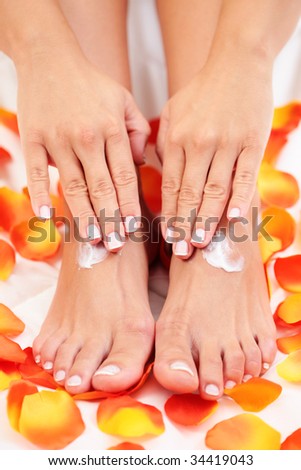 female hands and feet with petal of rose - beauty treatment