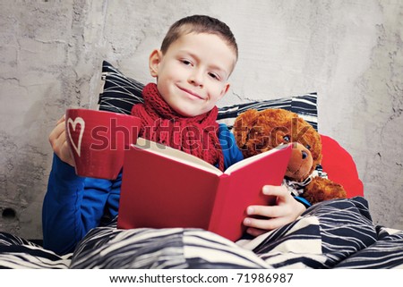 9 years old boy ill reading book in bed - kids and family