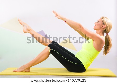 Fit young blonde pilates instructor showing different exercises with basic sport equipment including  yoga mat