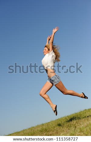 Young jumping woman on the green summer field