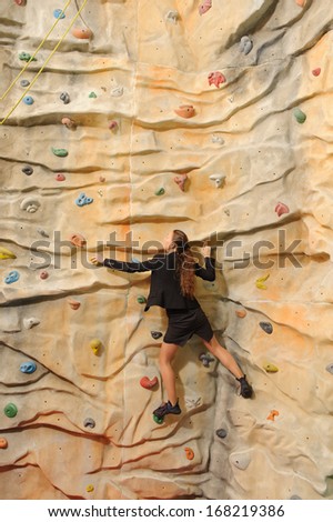 active young business woman on rock wall in sport center