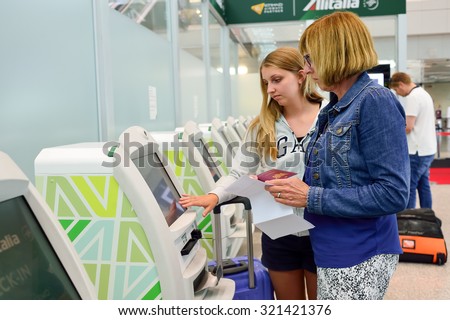 ROME, ITALY - AUGUST 16, 2015: women use self check-in kiosks in Fiumicino Airport. Fiumicino - Leonardo da Vinci International Airport is a major international airport in Rome, Italy
