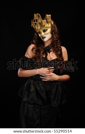 sexy evil woman in black dress and golden half mask hold rose, isolated on black