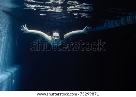 Woman in summer dress swimming under water in the pool