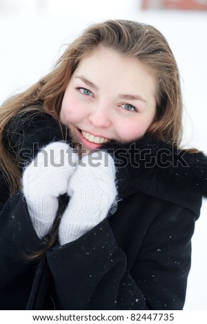 young pretty smiling woman in winter warming with gloves and coat outdoors