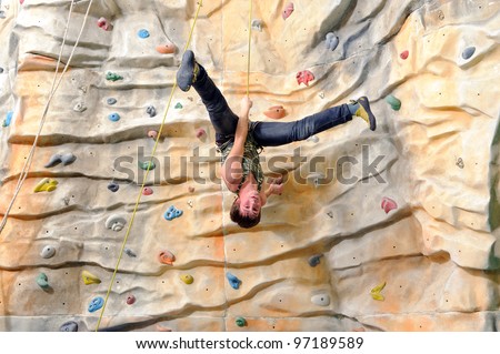 active young man on rock wall in sport center