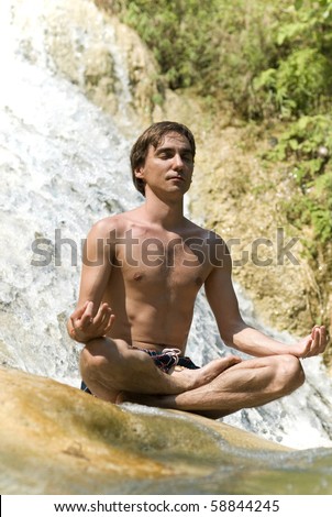 A man meditating by a waterfall.