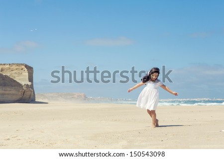Little girl dancing on the beach with a white dress