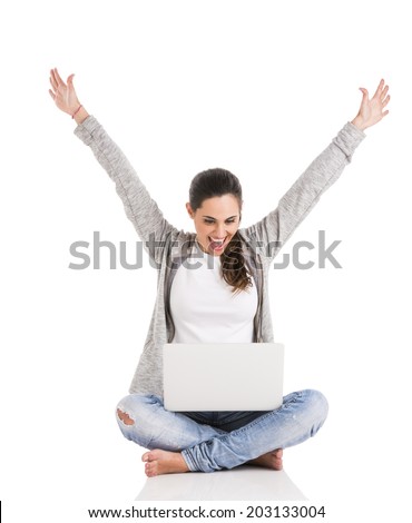 Beautiful happy woman with arms up sitting with crossed legs and working with a laptop