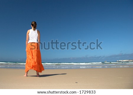 Beautiful woman in the beach with a orange skirt