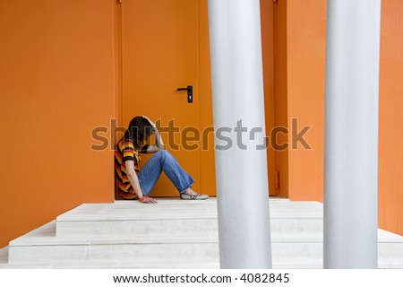 Loneliness woman on a orange door with hands over the knees