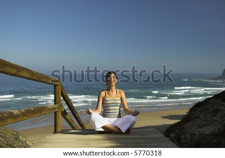 Beautiful young woman doing yoga on the beach