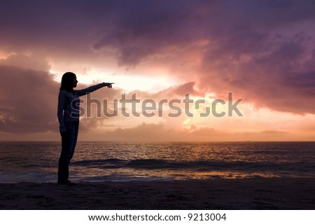 Woman silhouette relaxing on the beach and looking to the sunset
