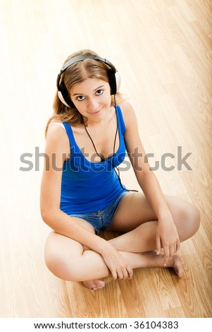 Beautiful young woman sitting on floor listen music