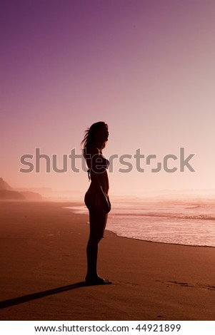 Female silhouette of a beautiful young girl on the beach at the sunset