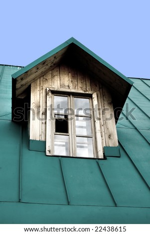 A window on top of a wooden house with a green roof