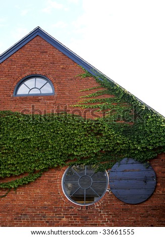a round window on a brick building with green ivy