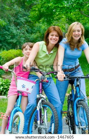 A mother and two daughters clown around on their bicycles for some summer fun.