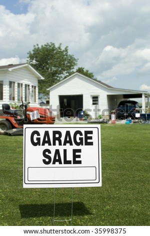 A garage sale sign with garage and items in background. Room for copy.