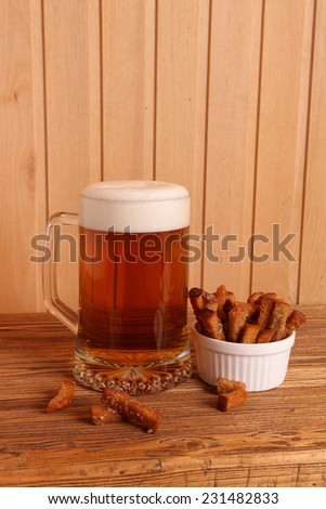 Mug with light beer and salty crackers on a wooden table