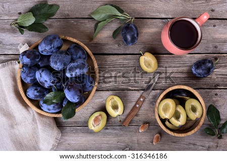 Ripe plums and plum juice on a wooden table, top view