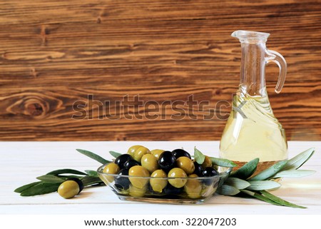 Olives and olive oil on a white table on wooden background, copy space