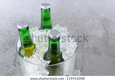 Three green beer bottles in a crystal ice bucket.