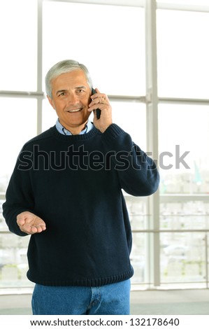 Closeup of a casual businessman in a modern office talking on his cell phone. Vertical Format.
