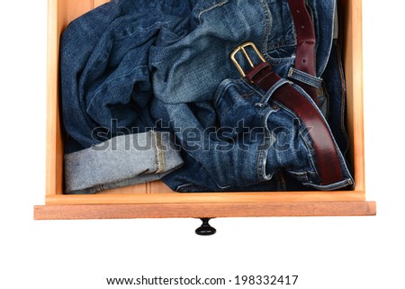 High angle shot of a pair of blue jeans crumpled up in a dresser drawer. Horizontal format isolated on white.