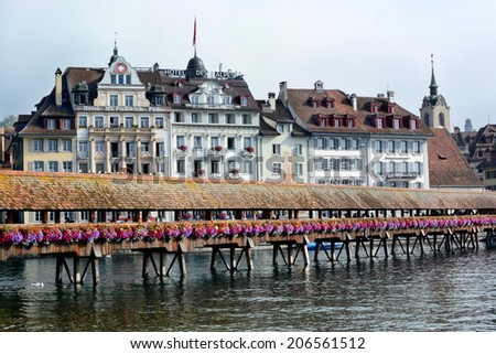 LUCERNE, SWITZERLAND - JULY 2, 2014: Chapel Bridge and Hotels on the Reuss River, Lucerne. The Chapel Bridge spans the Reuss with the Hotel Des Alpes and Mr. Pickwick Pub in background.