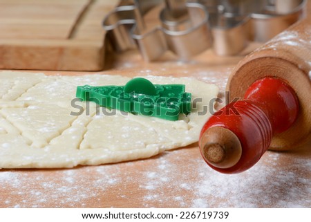Closeup Christmas baking still life with rolling pin, cookie dough, cutters and flour on a wood butcher block surface.