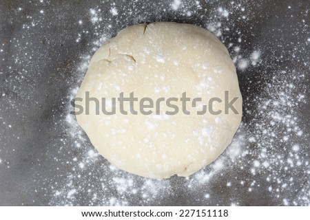 Overhead shot of a ball of dough on a baking sheet sprinkled with flour. Horizontal format.