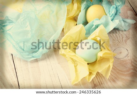 High angle view of pastel Easter eggs wrapped with tissue paper. Shallow depth of field with focus on the front egg. Intentional instagram effect added.