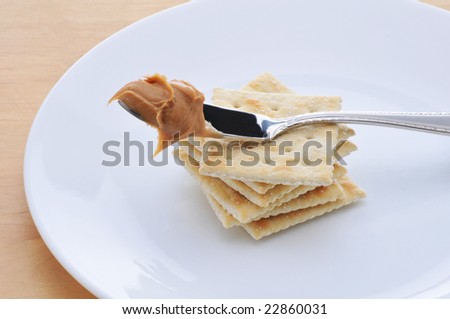 Peanut Butter on knife resting on a stack of crackers
