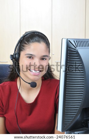 Smiling receptionist at computer talking on headset vertical format