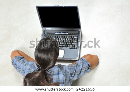 Teenage girl laying on the floor with laptop - view from above - shoulders and back of head