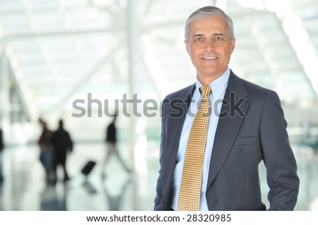 Mature Business Traveler in Airport Concourse with blurred travelers in background