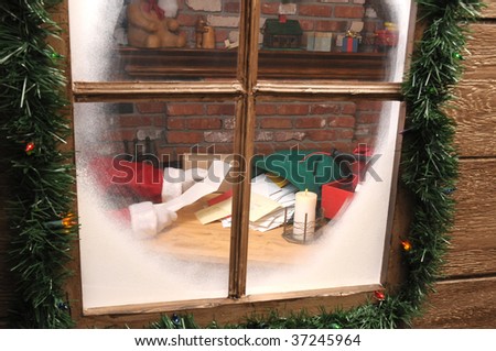 Santa Claus Sitting in His Workshop reading a letter seen through window. horizontal Composition.