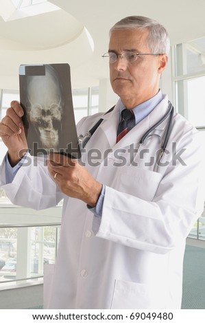 Middle Aged Doctor in Lab Coat with X-ray. Vertical composition in modern medical facility.