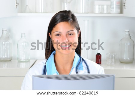 Young Female Medical Professional looking over the top of her computer. Horizontal format with out of focus background.