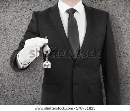 businessman gives a key on concrete background