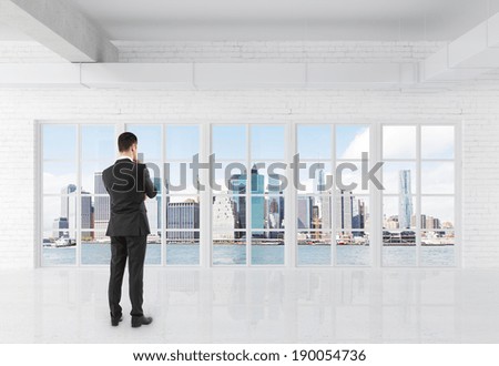businessman in suit standing in room and looking at window