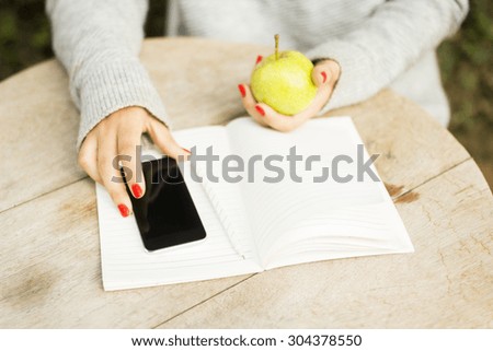 girl with cell phone, diary and green apple