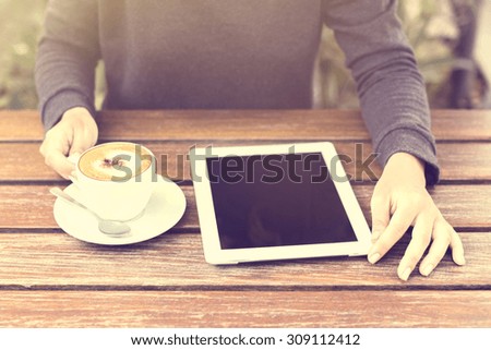 Girl with digital tablet and cup of coffee at sunrise
