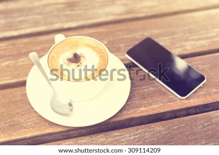 cell phone and cup of coffee on the table