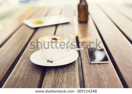 cell phone and cup of coffee on a table outdoors