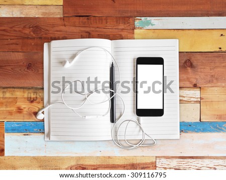 Blank cell phone, notebook and headphones on a wooden background